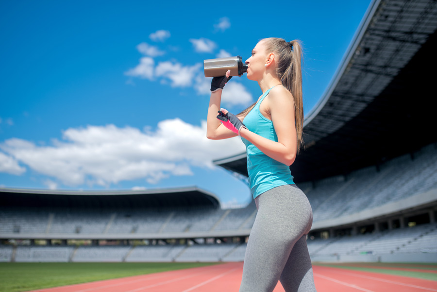 Healthy fitness girl drinking protein