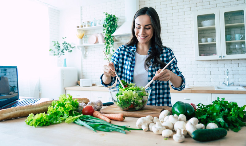 Young woman preparing vegetable salad